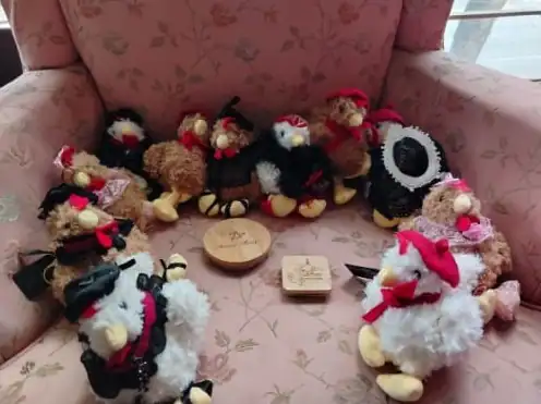 Grupo de GallinAsspas vestidas con boinas, capas y encaje sobre un sillón rosa